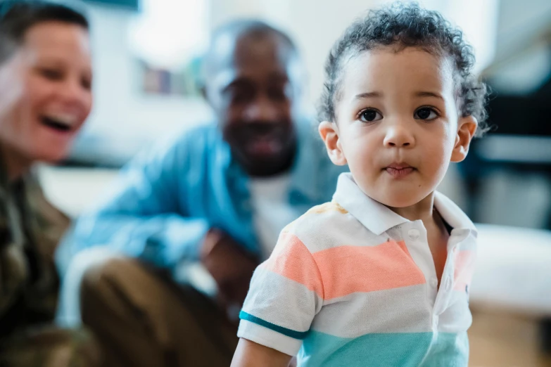 a little girl sits on the floor as an older man is behind her