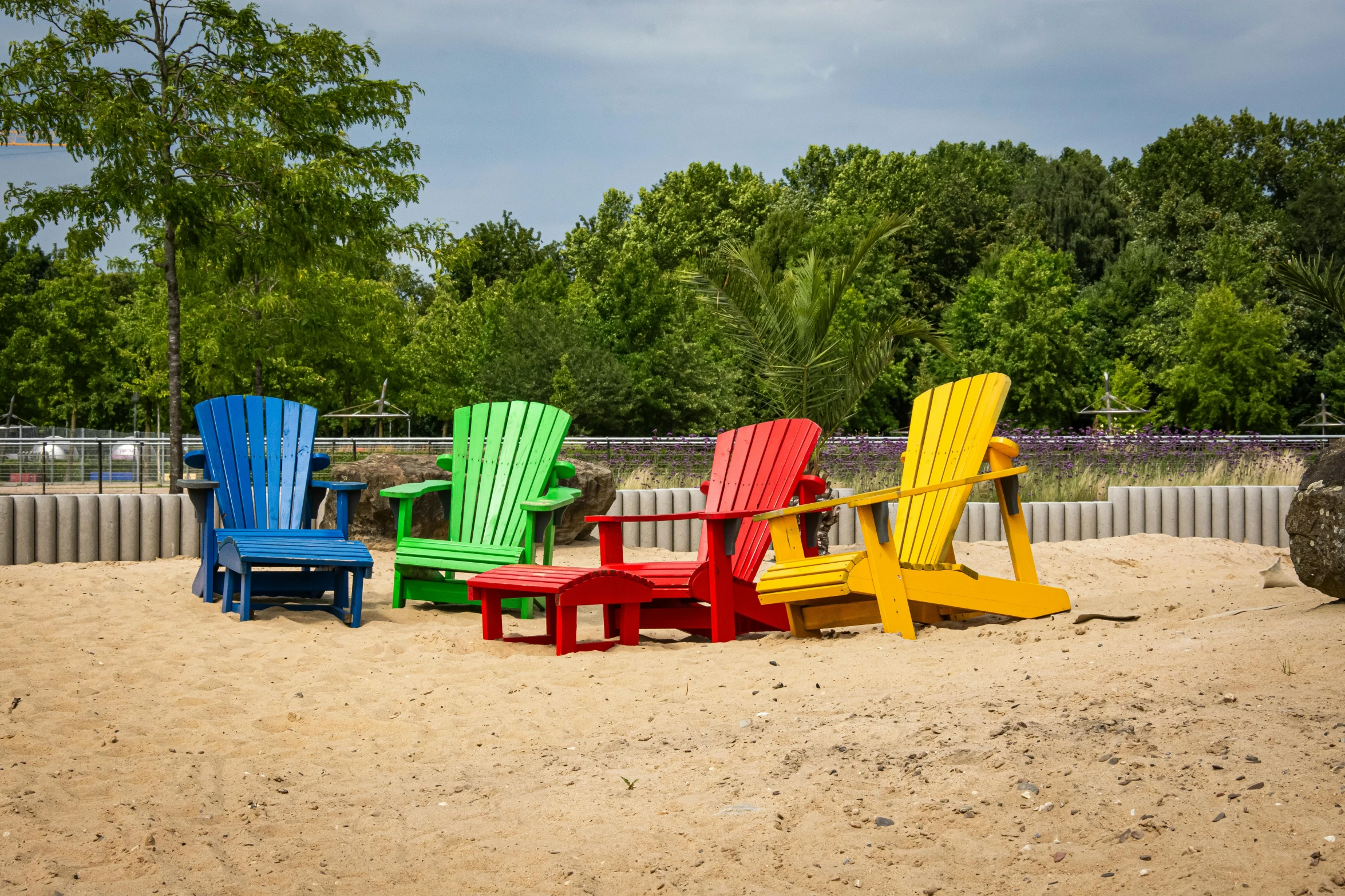 a rainbow colored wooden adirondack in the sand