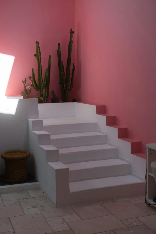 a white stair case leading up to a bright pink wall