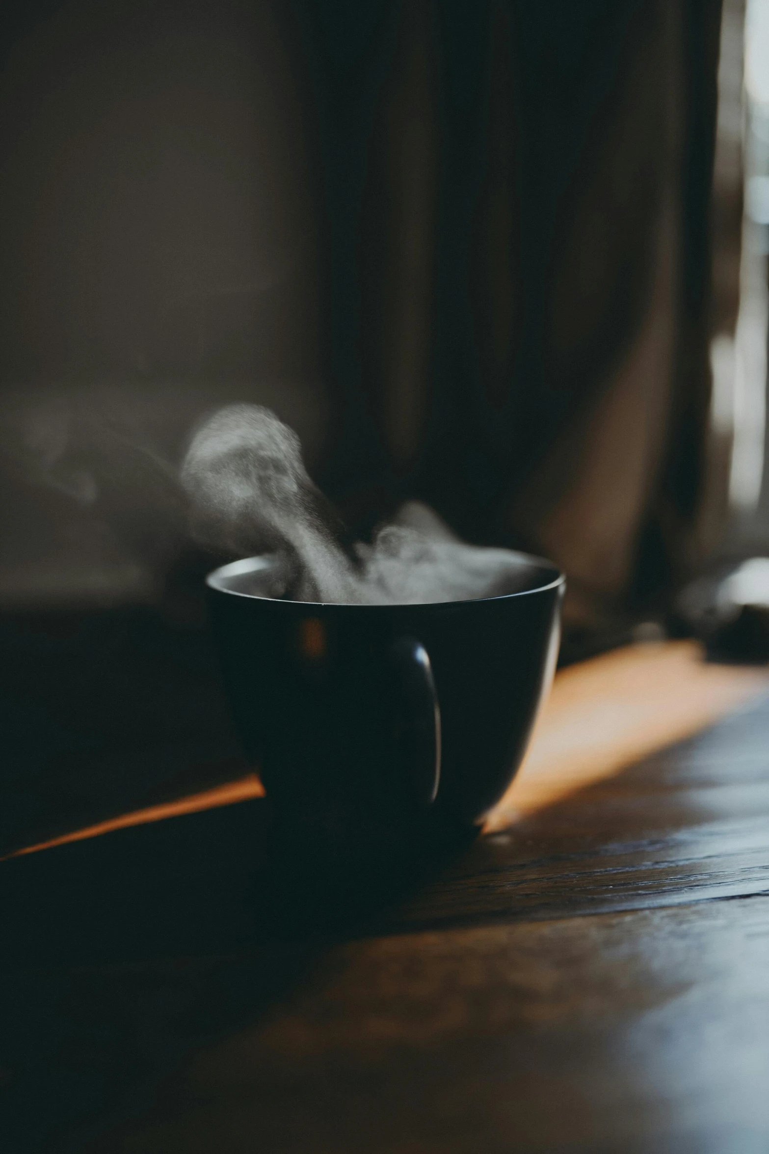 a steaming black bowl on a wooden surface