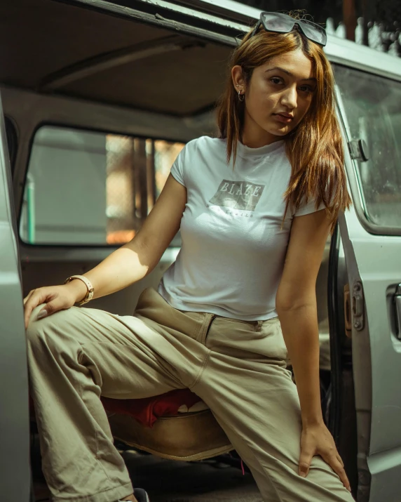 a woman in sunglasses sitting next to a car