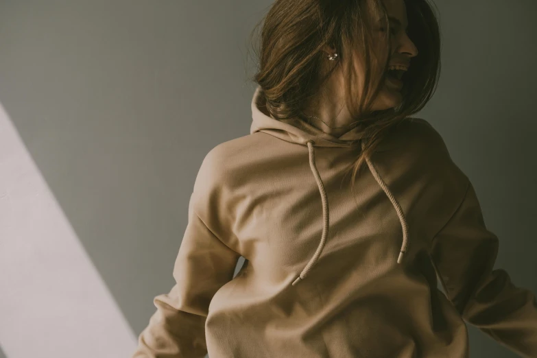 a woman standing and wearing a brown sweatshirt and tan pants