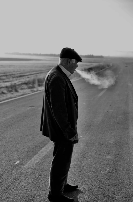 a black and white po of a man in a suit and hat standing on a road