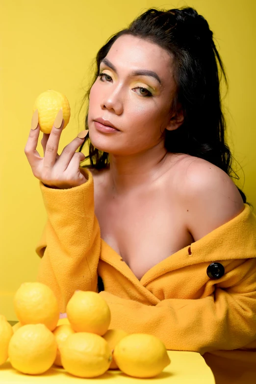 woman in orange robe sitting next to lemons holding a hand