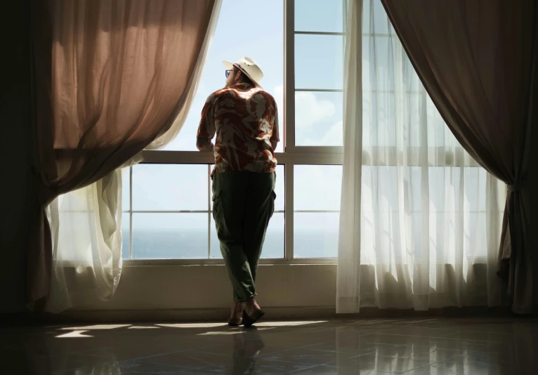 a woman looking out the window in front of the ocean