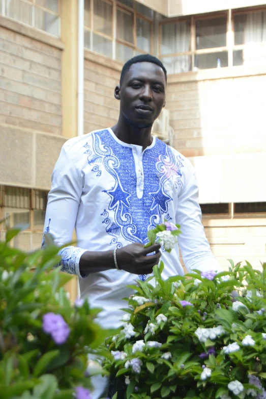 man in blue and white shirt holding a flower in his hand