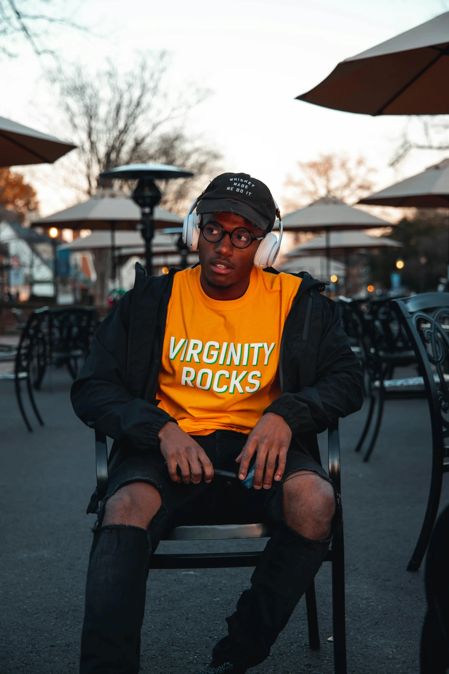 a man wearing an orange shirt is sitting on a bench outside