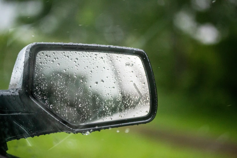 a close up of a car's mirror with raindrops