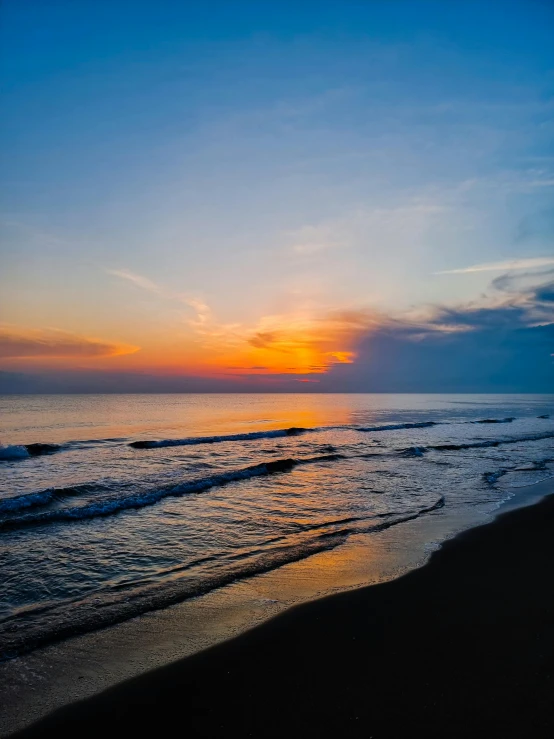 a sunset is seen over a beach and ocean