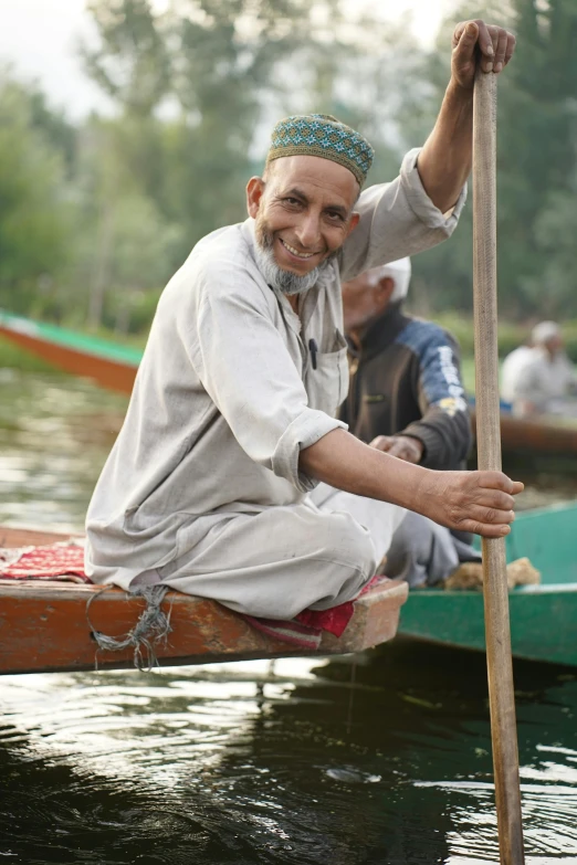 the older man is sitting in the canoe with his oar