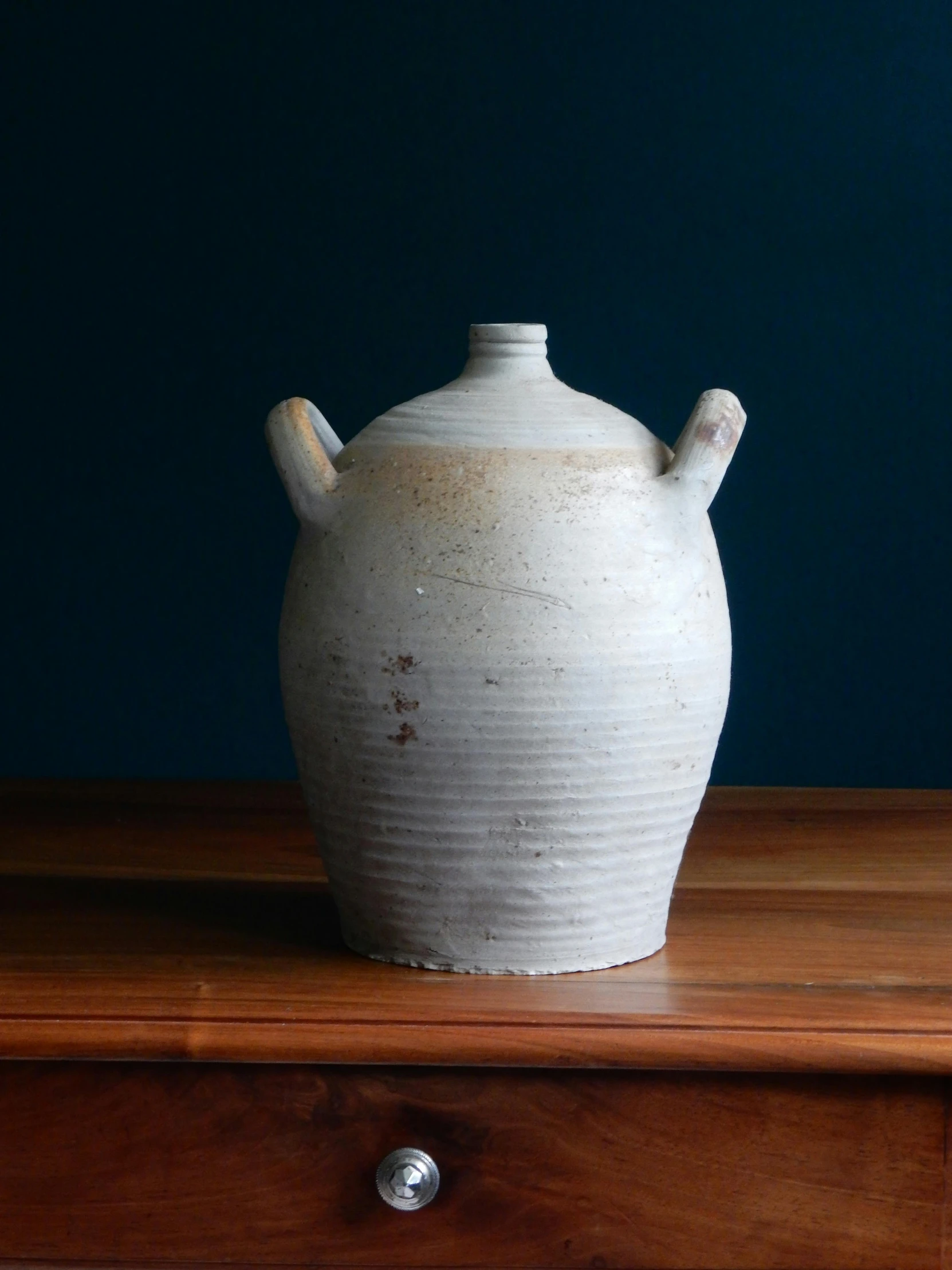 a white vase sitting on top of a wooden table