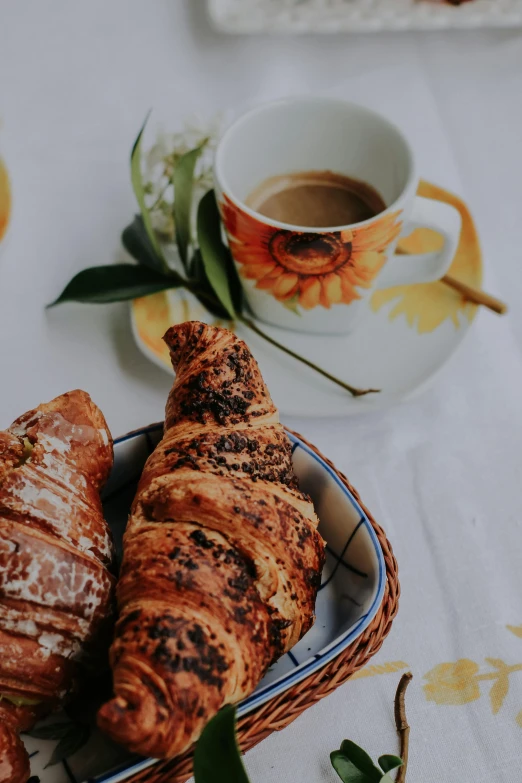 croissants on a plate next to coffee and orange flowers