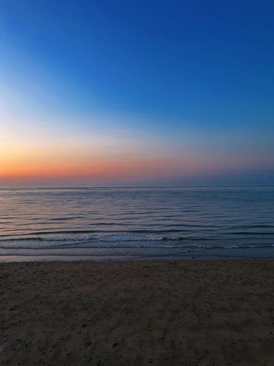 the sun is setting over the water near the beach