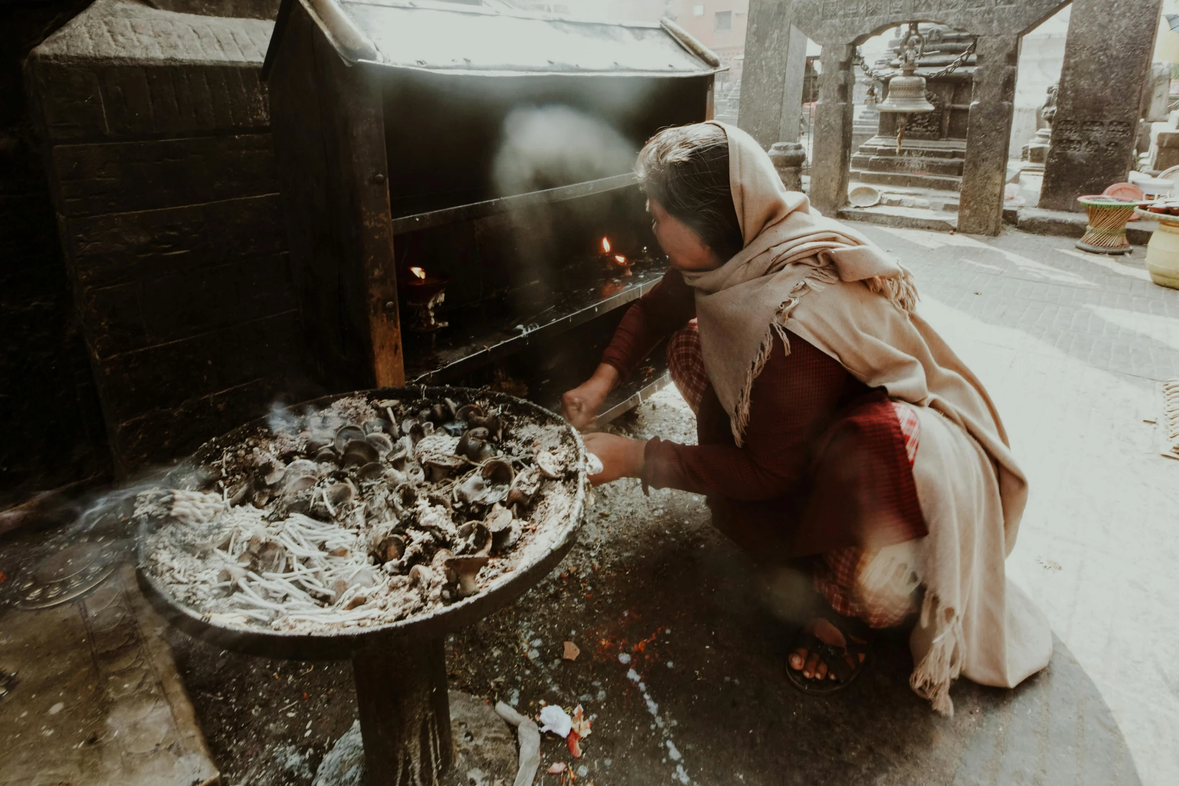 a woman placing pizza on an outdoor oven