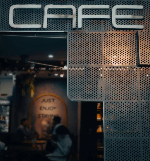 the sign for a cafe, the restaurant is painted with an array of metallic mesh panels