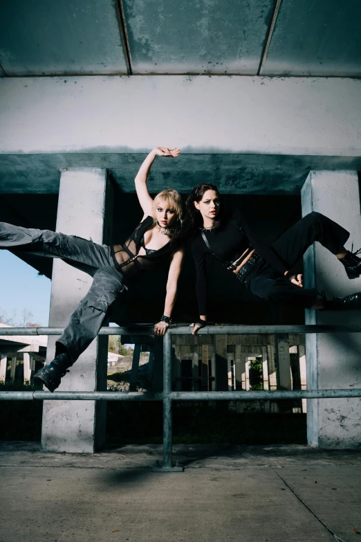 two dancers jumping off of a metal barricade