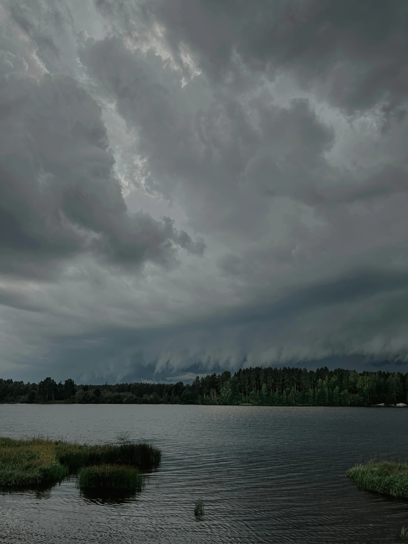 dark clouds are floating in the sky above a body of water