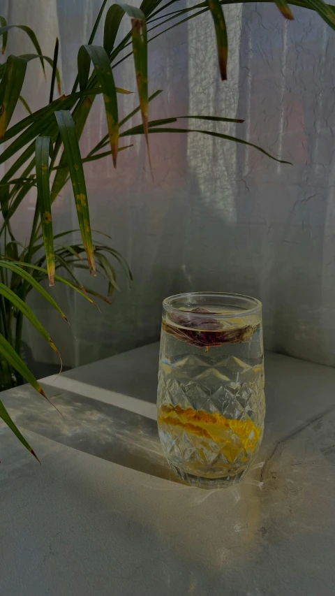 a glass filled with ice and yellow liquid sitting on top of a table