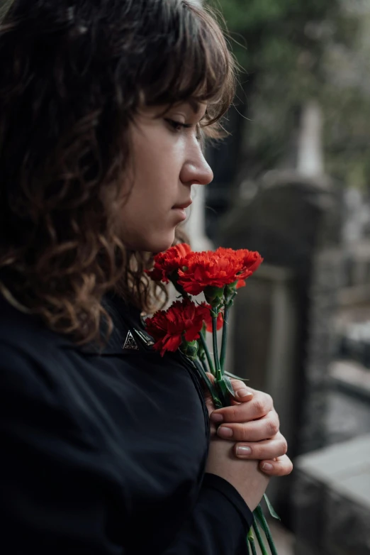 a woman in black jacket holding red flowers