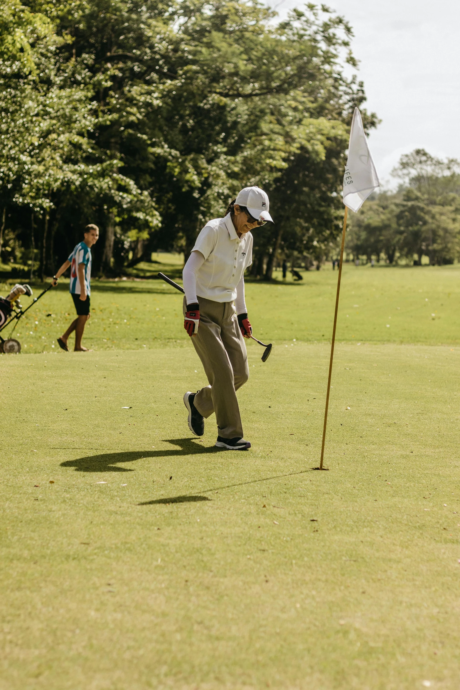 a man in a hat and white jacket playing golf