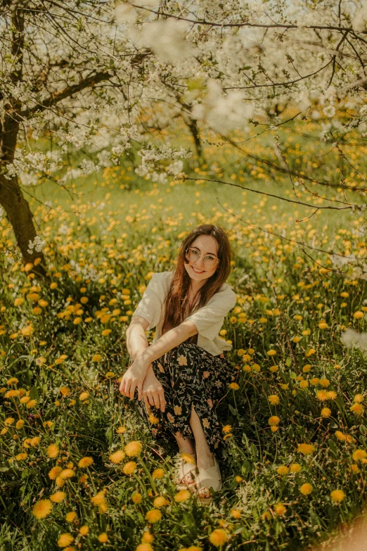 a girl sitting in the grass surrounded by wildflowers