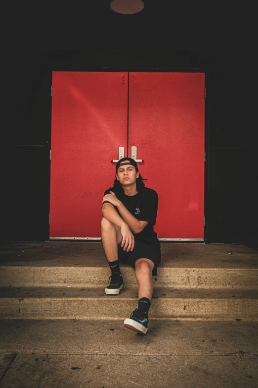 a man sitting on steps in front of a large red screen