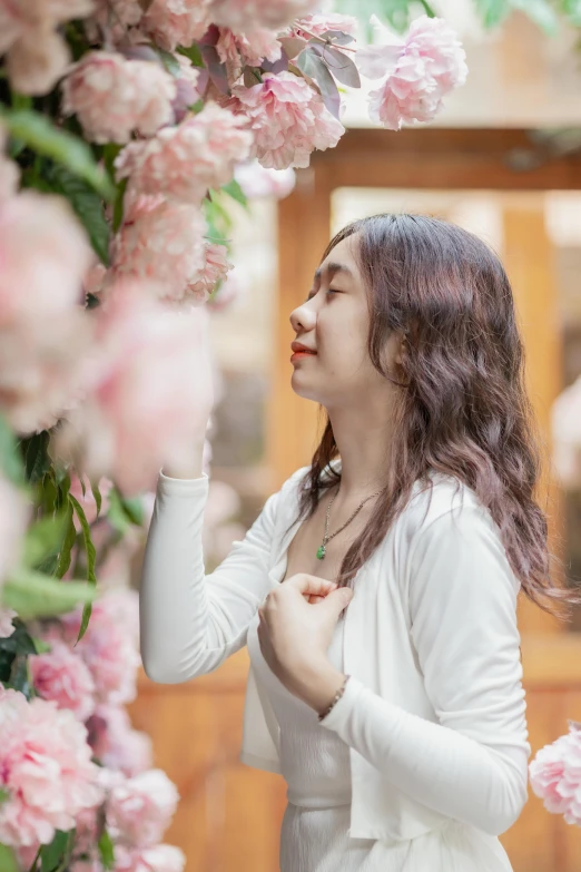 a woman in white is standing by some pink flowers