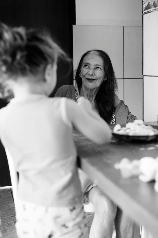 the small girl is standing on a counter looking at the woman