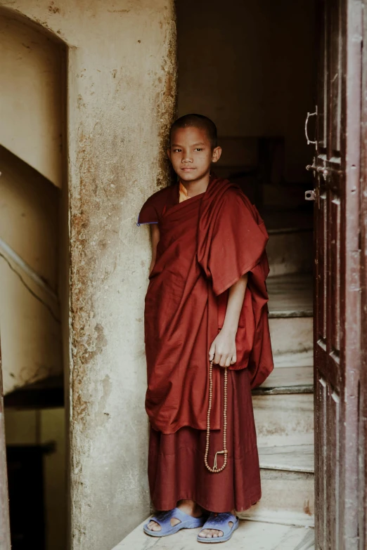 the young monk stands in an alley by a building