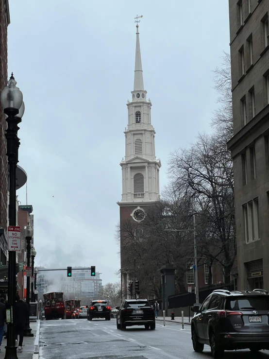 an intersection has a building with a steeple on the top and trees along side