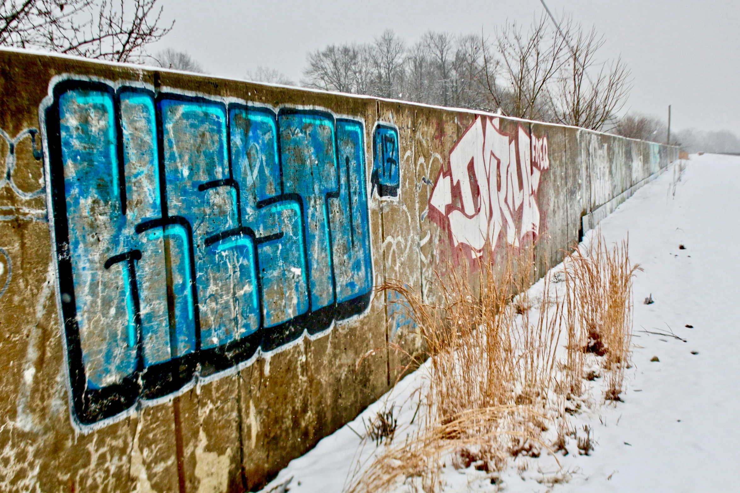 a concrete fence sitting next to a snow covered field