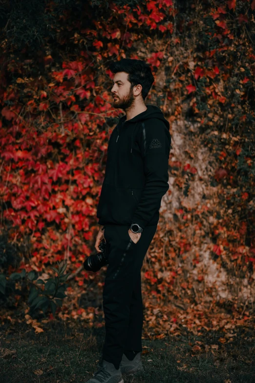 a man standing near a red plant next to a building