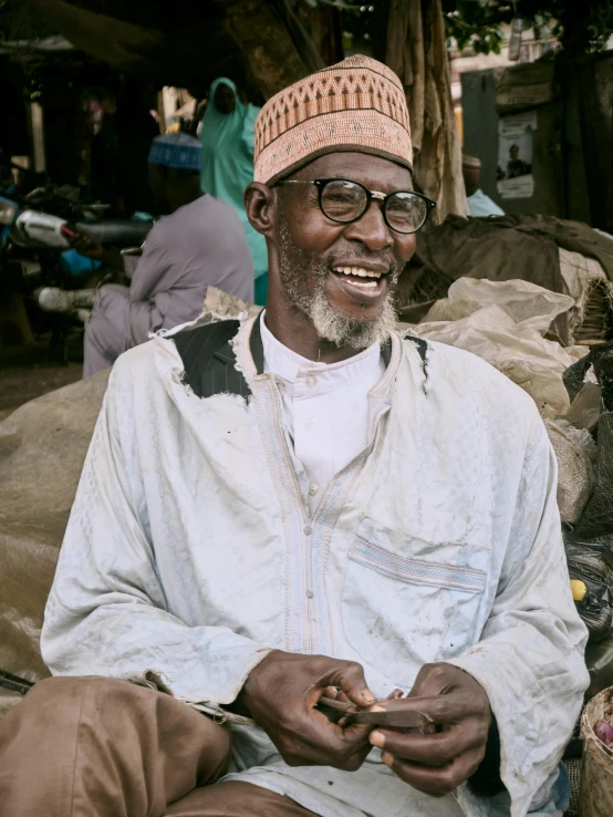 an older man sitting next to bags of fruit