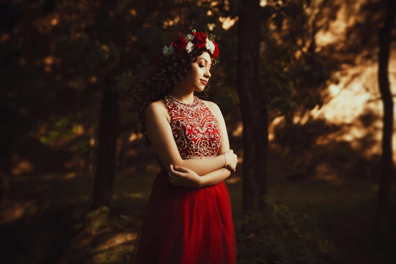 a woman with a flower in her hair, stands in the forest with trees and holds her hands on his waist