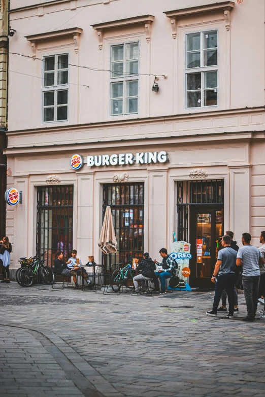 people sitting and standing outside of burger king in a city