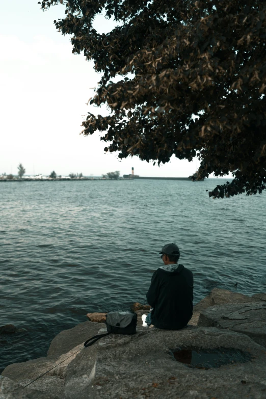 a man sits on some rocks near the water