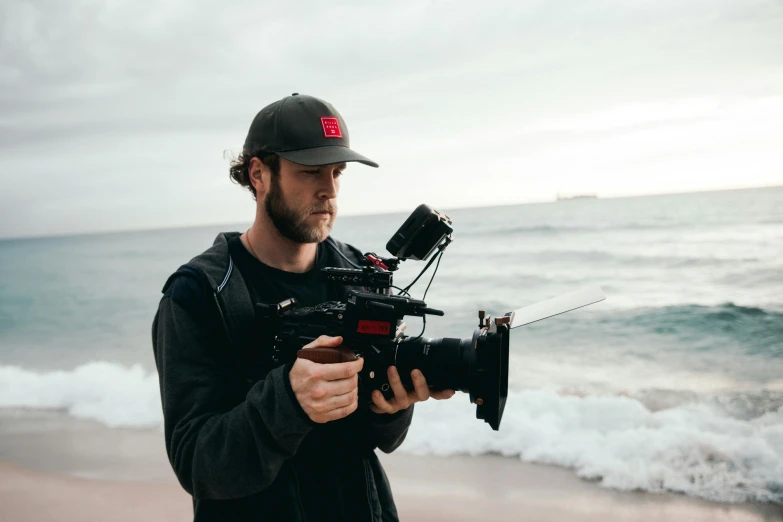 a man stands on the beach while holding a camera