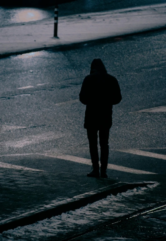 a man in black coat standing on street with umbrella