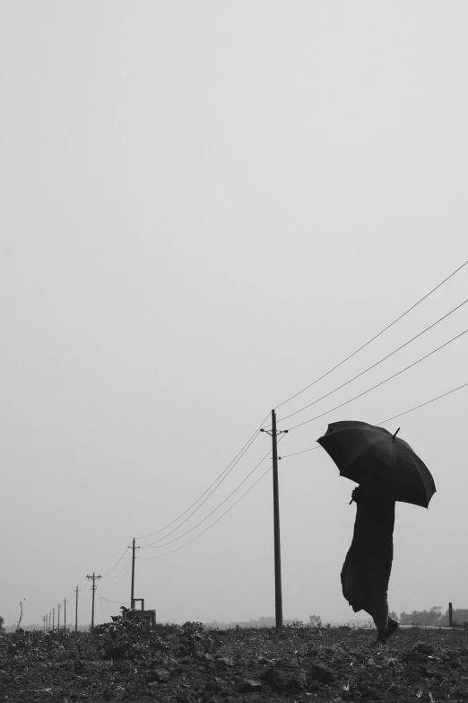 a person walking in a field under an umbrella