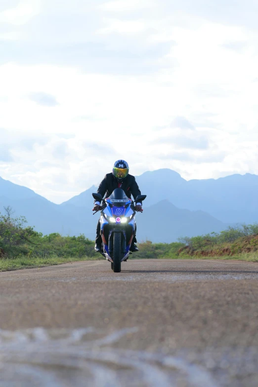 a motorcycle rider riding down the middle of a dirt road