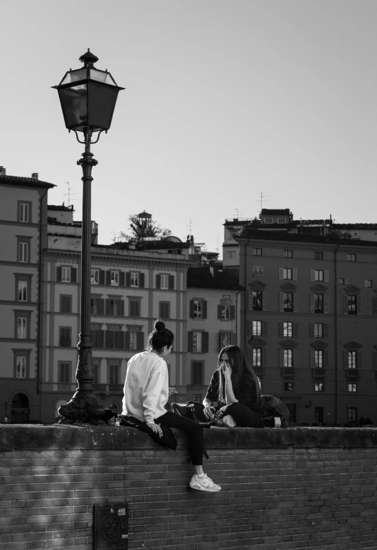 people sitting on a wall near some city lights