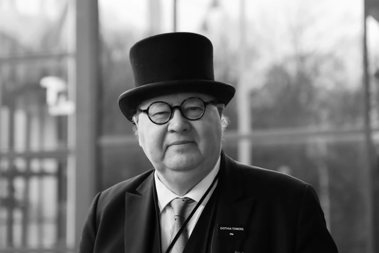 an older gentleman wearing a top hat, suit and glasses