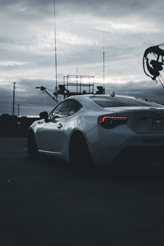 a white sports car parked at a street with other vehicles behind it