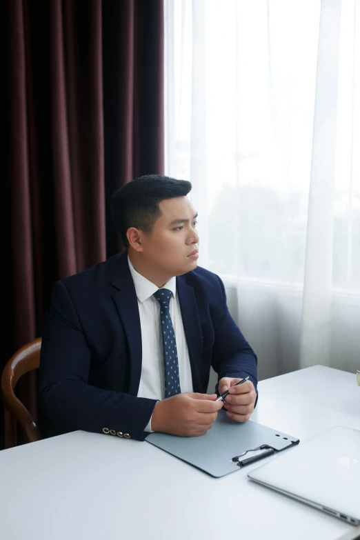 a man wearing a suit sits at a desk