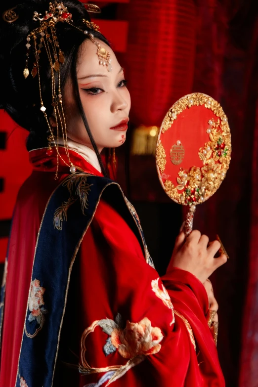 a woman is dressed in traditional chinese garb holding a red fan