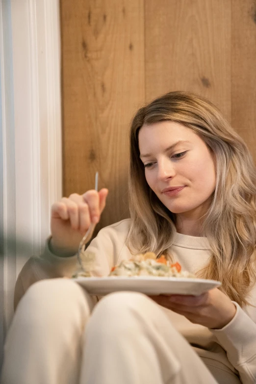 a beautiful woman eating soing at her plate while sitting