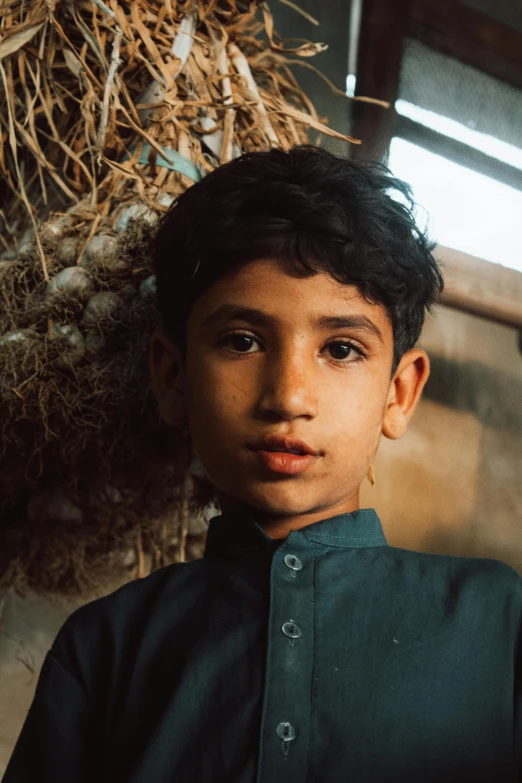 a boy is standing near a bunch of sticks