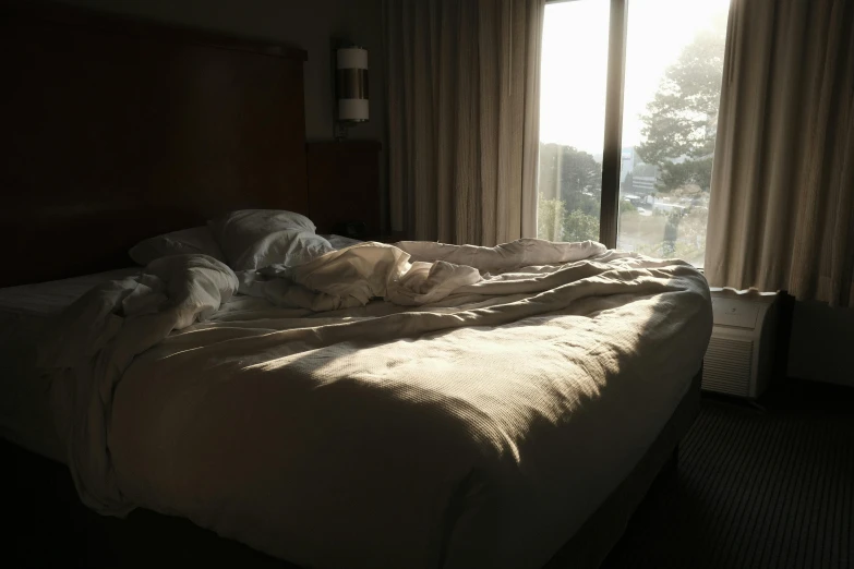 a bed covered in a blanket and pillows near a window