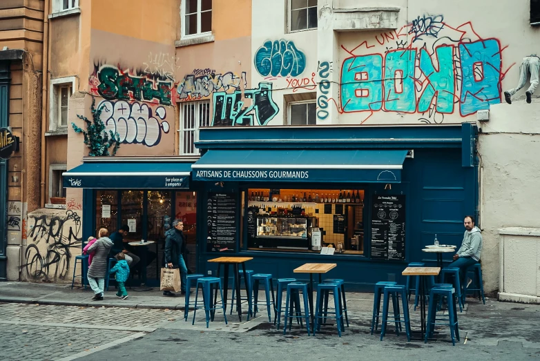 a blue restaurant with people eating at it and graffiti on the wall