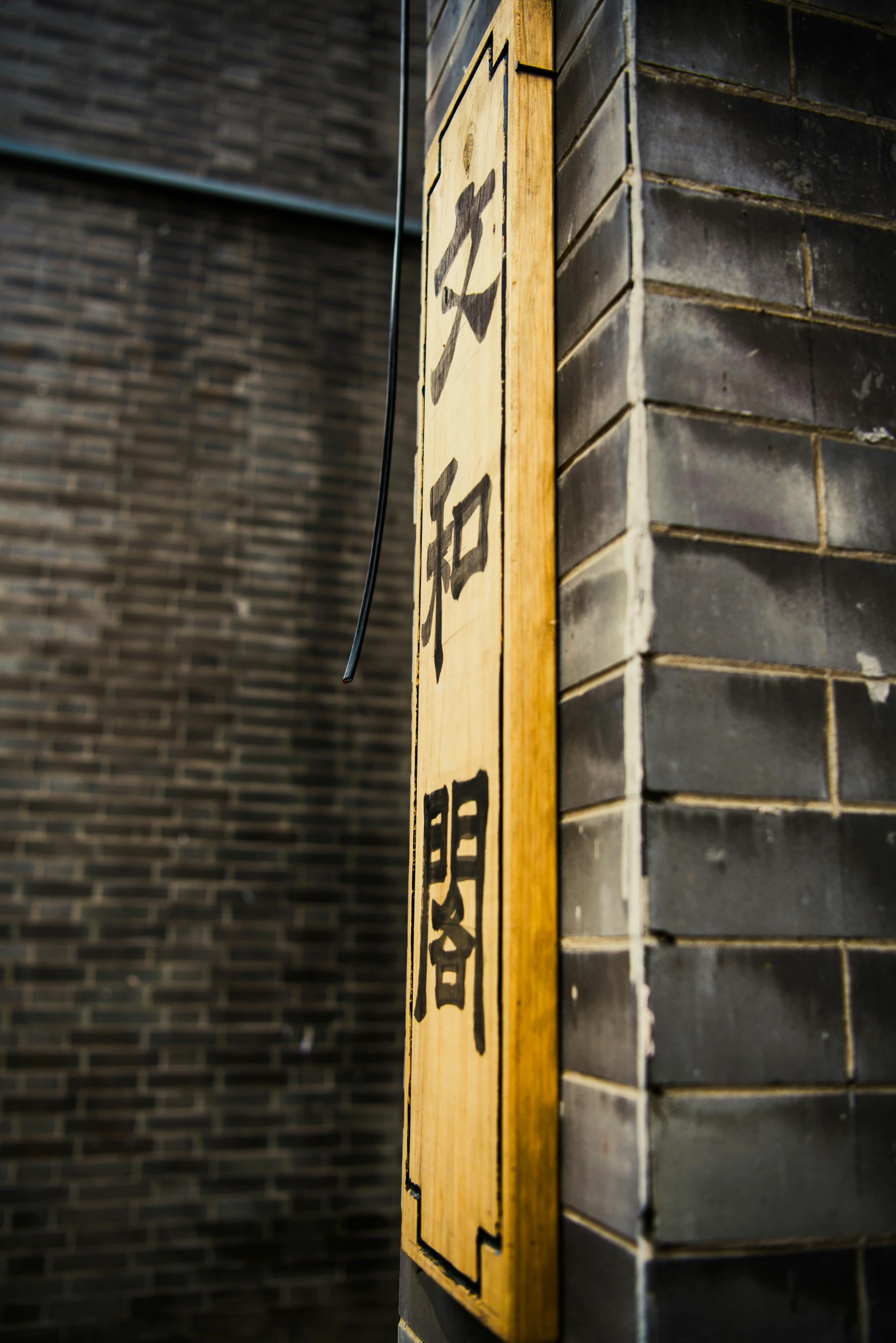 the asian style signage is leaning up against a brick wall